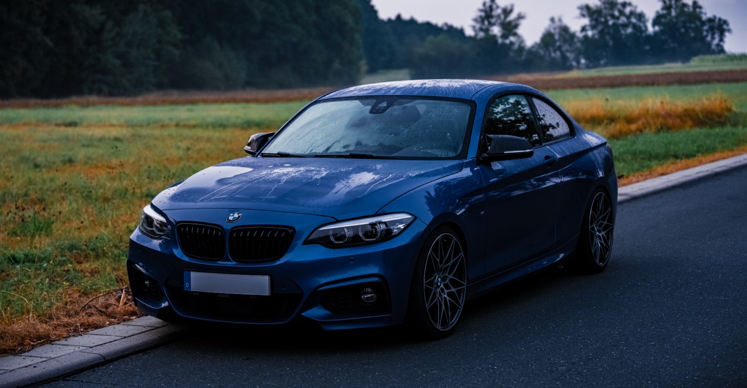 Blauer BMW auf einer Landstraße nach dem Regen