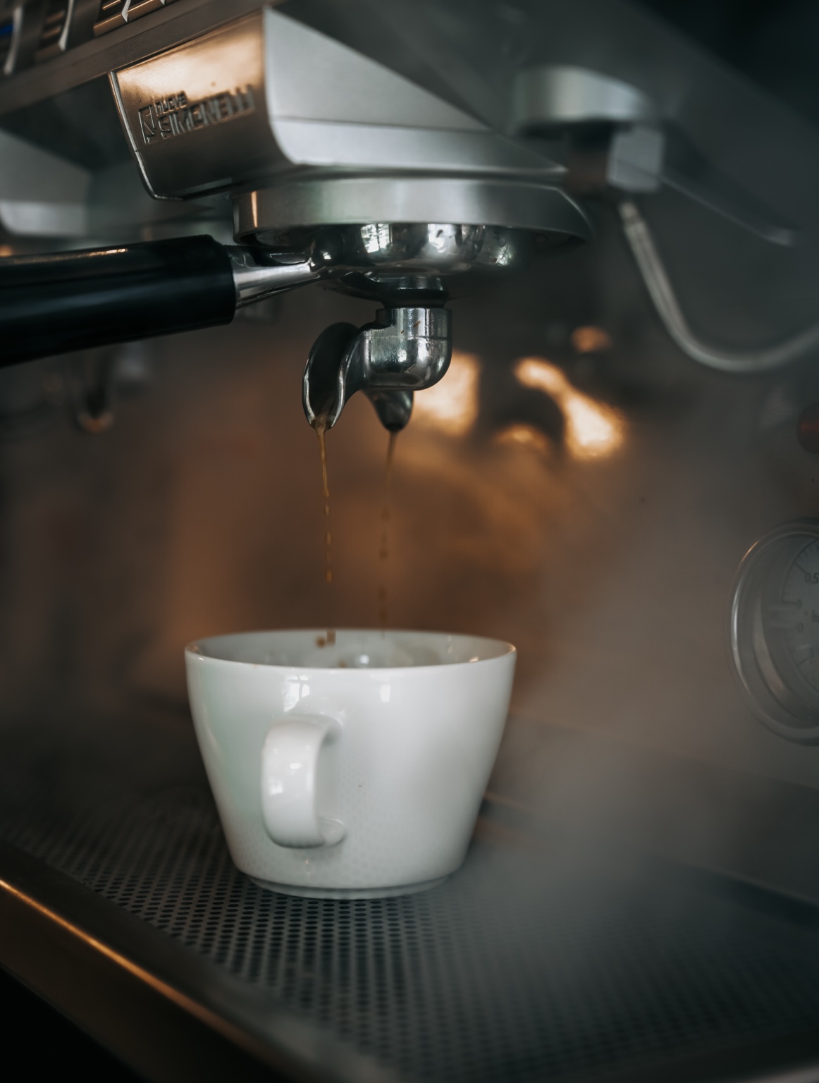 Espresso läuft aus einem Siebträger in eine weiße Tasse